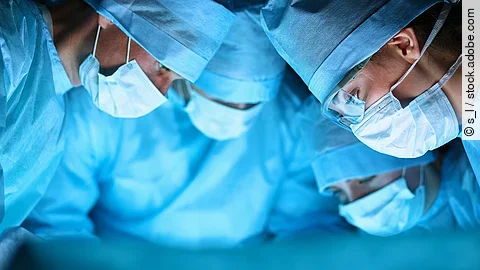 Ärzteteam Ärzteteam in OP-Kleidung über einem OP-Tisch geneigt.