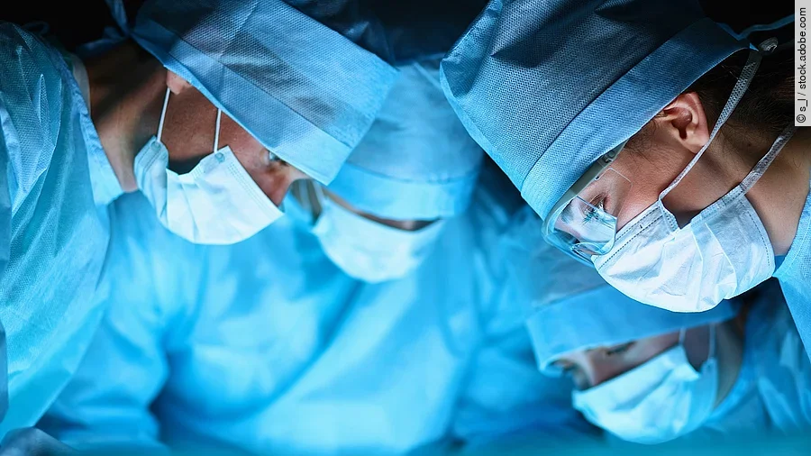 Ärzteteam in OP-Kleidung über einem OP-Tisch geneigt.