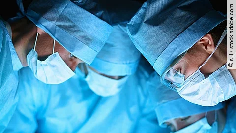 Ärzteteam in OP-Kleidung über einem OP-Tisch geneigt.