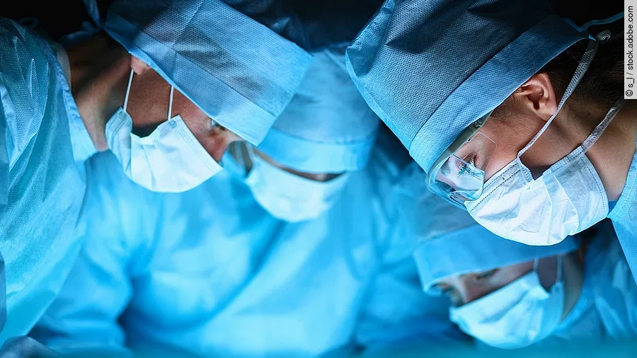 Ärzteteam in OP-Kleidung über einem OP-Tisch geneigt.