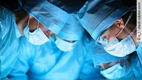 Ärzteteam in OP-Kleidung über einem OP-Tisch geneigt.