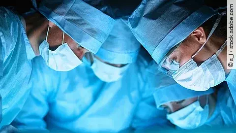 Ärzteteam in OP-Kleidung über einem OP-Tisch geneigt.