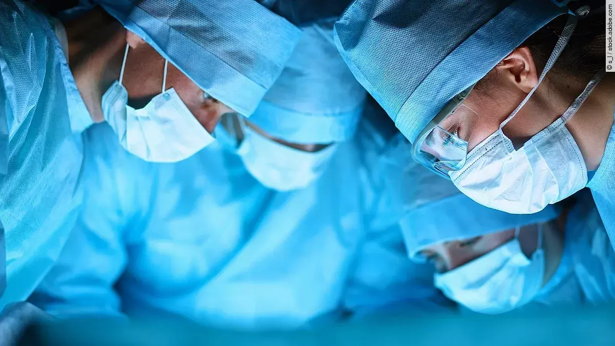 Ärzteteam Ärzteteam in OP-Kleidung über einem OP-Tisch geneigt.