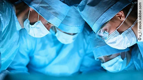 Ärzteteam in OP-Kleidung über einem OP-Tisch geneigt.