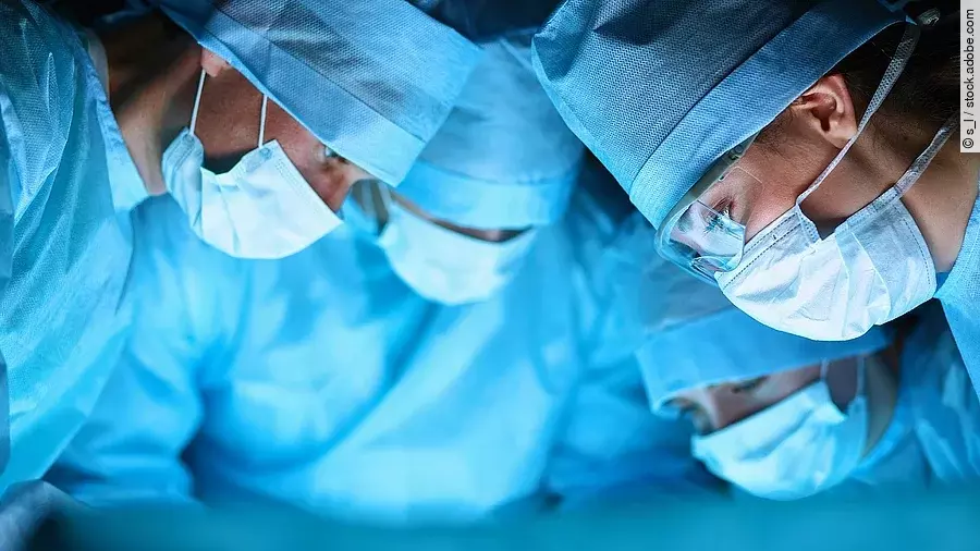 Ärzteteam in OP-Kleidung über einem OP-Tisch geneigt.