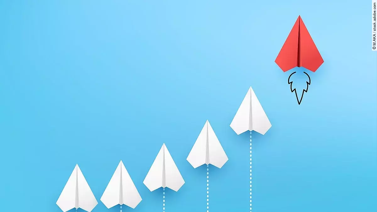 Sechs Papierflieger, die kurvenähnlich angeordnet sind vor blauem Hintergrund. Der rechte und höchste Papierflieger ist rot.