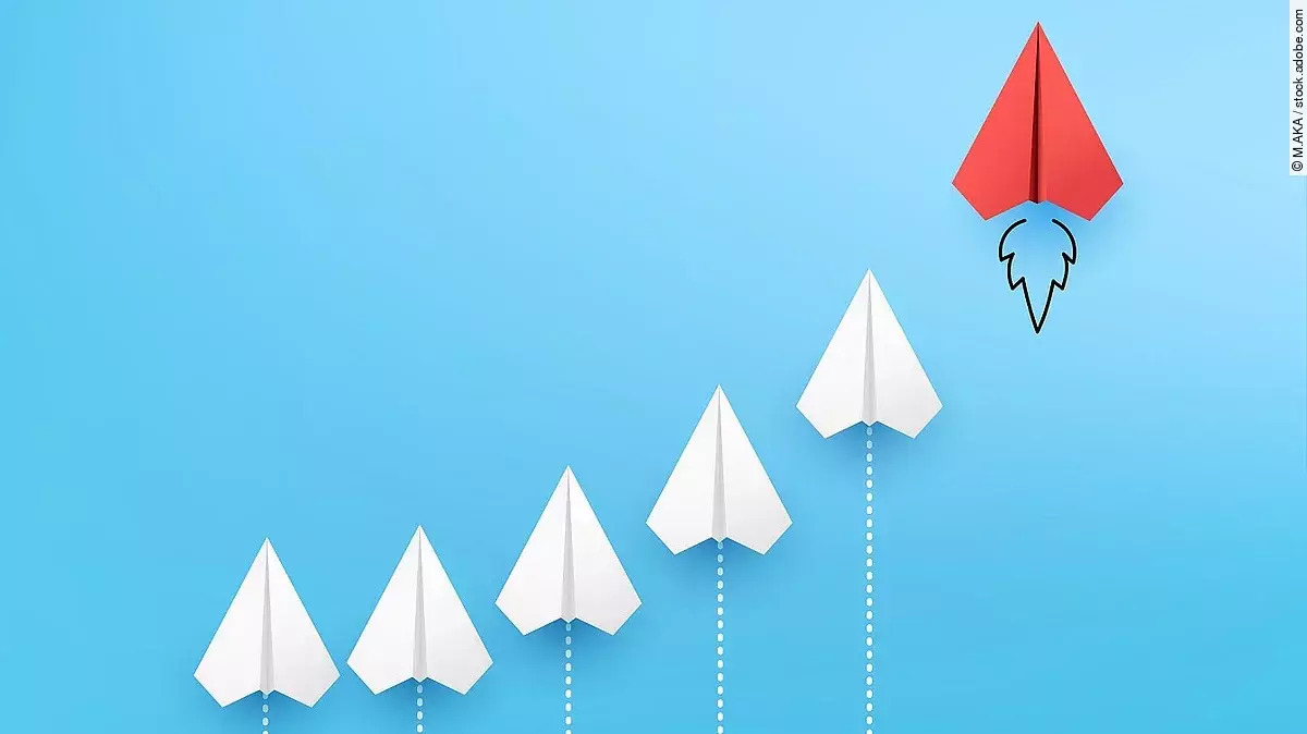 Sechs Papierflieger, die kurvenähnlich angeordnet sind vor blauem Hintergrund. Der rechte und höchste Papierflieger ist rot.