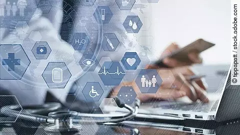 Cloud Ein Mann sitzt an seinem Laptop. Daneben liegt ein Stethoskop. Im Vordergrund erscheint eine holografische Darstellung aus vielen einzelnen Icons und Symbolen, die ein digitales Netzwerk aus Daten verkörpern sollen.