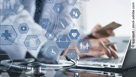 Generative KI Ein Mann sitzt an seinem Laptop. Daneben liegt ein Stethoskop. Im Vordergrund erscheint eine holografische Darstellung aus vielen einzelnen Icons und Symbolen, die ein digitales Netzwerk aus Daten verkörpern sollen.