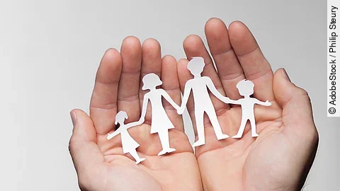 Zwei Hände bilden eine Schale, darin sind die Umrisse einer Familie mit Mutter, Vater und zwei Kindern zu sehen.