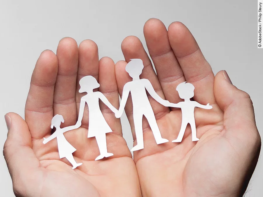 Zwei Hände bilden eine Schale, darin sind die Umrisse einer Familie mit Mutter, Vater und zwei Kindern zu sehen.