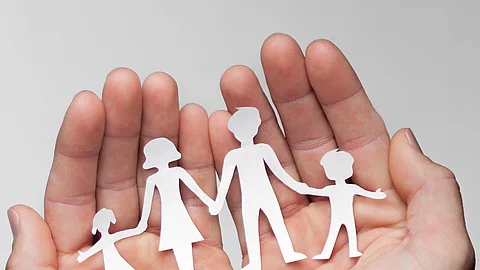 Zwei Hände bilden eine Schale, darin sind die Umrisse einer Familie mit Mutter, Vater und zwei Kindern zu sehen.