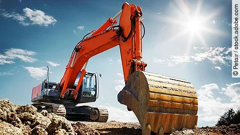 Bagger Ein organe-farbener Bagger steht auf einem Schutthaufen.