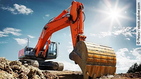 Bagger Ein organe-farbener Bagger steht auf einem Schutthaufen.