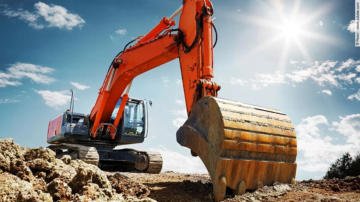 Bagger Ein organe-farbener Bagger steht auf einem Schutthaufen.