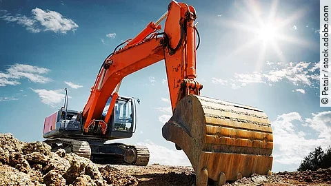 Bagger Ein organe-farbener Bagger steht auf einem Schutthaufen.