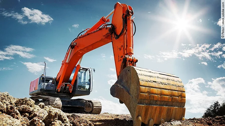 Bagger Ein organe-farbener Bagger steht auf einem Schutthaufen.