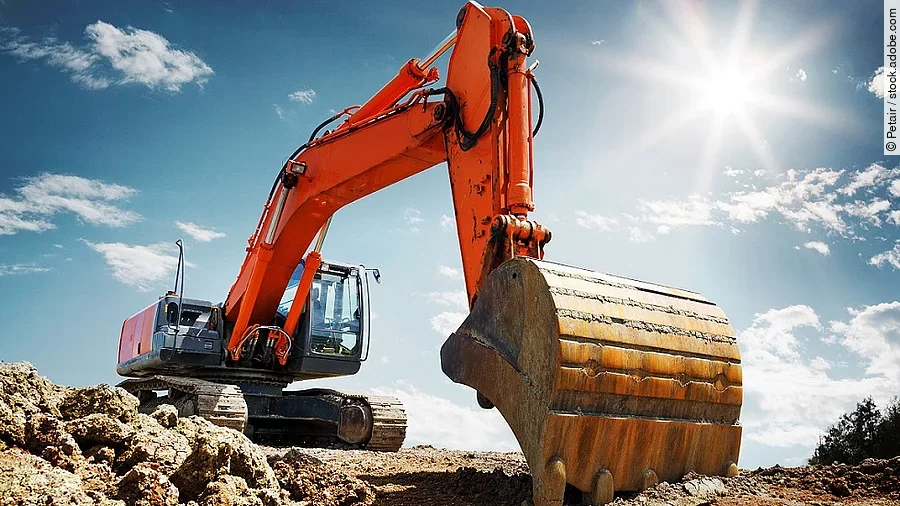 Bagger Ein organe-farbener Bagger steht auf einem Schutthaufen.