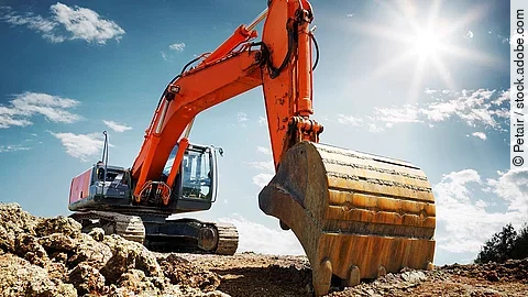 Bagger Ein organe-farbener Bagger steht auf einem Schutthaufen.