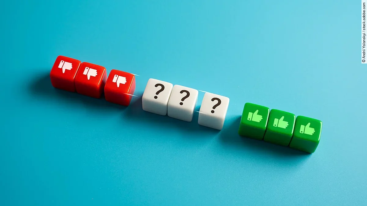 Daumen runter, Fragezeichen und Daumen hoch-Symbole aneinandergereiht auf roten, weißen und grünen Würfeln