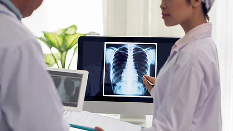 Frau deutet mit Kugelschreiber auf Röntgenbild