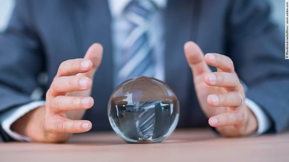 Zukunft Vor einem Anzugträger liegt eine Glaskugel auf dem Tisch.