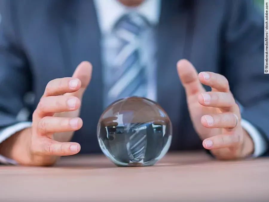 Zukunft Vor einem Anzugträger liegt eine Glaskugel auf dem Tisch.