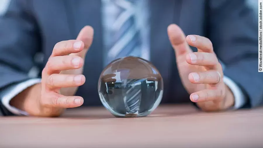 Zukunft Vor einem Anzugträger liegt eine Glaskugel auf dem Tisch.