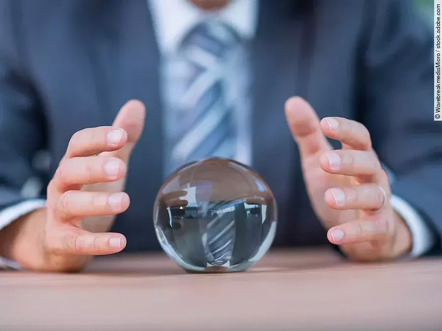 Zukunft Vor einem Anzugträger liegt eine Glaskugel auf dem Tisch.