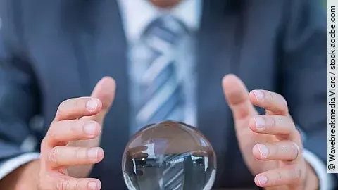 Zukunft Vor einem Anzugträger liegt eine Glaskugel auf dem Tisch.