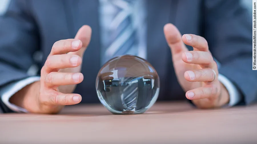 Zukunft Vor einem Anzugträger liegt eine Glaskugel auf dem Tisch.