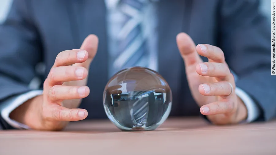 Zukunft Vor einem Anzugträger liegt eine Glaskugel auf dem Tisch.