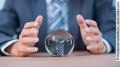 Zukunft Vor einem Anzugträger liegt eine Glaskugel auf dem Tisch.