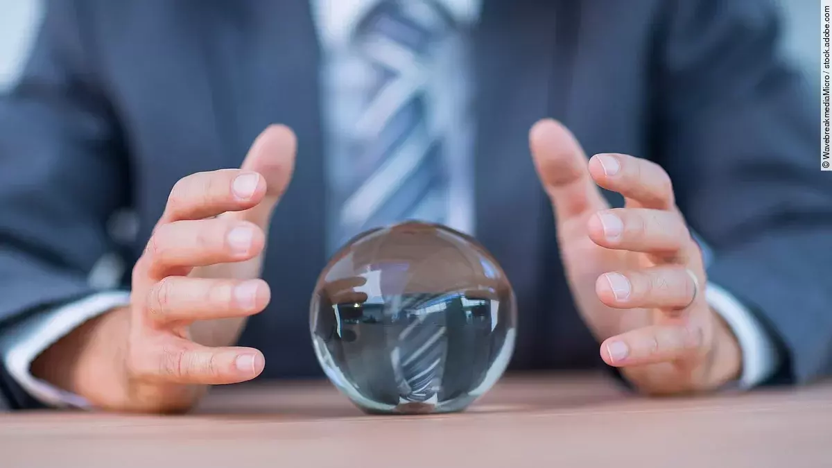 Zukunft Vor einem Anzugträger liegt eine Glaskugel auf dem Tisch.