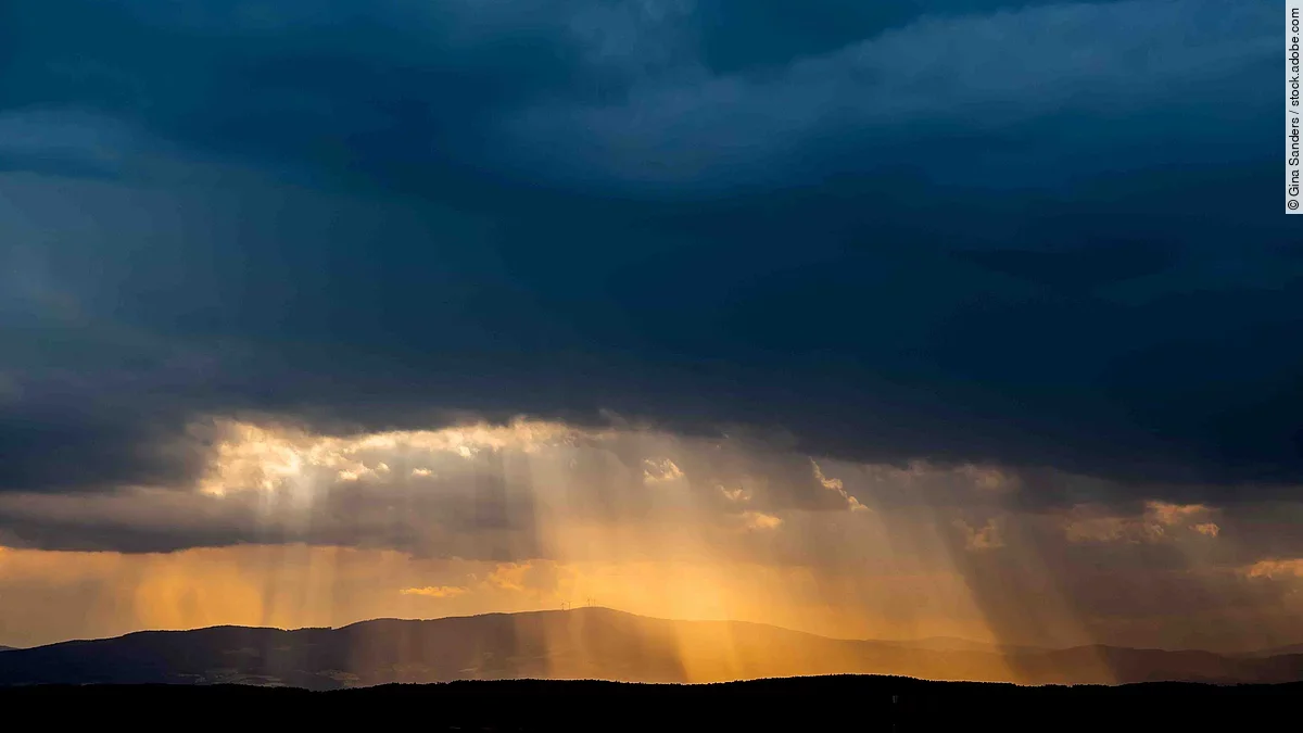 Sonnenstrahlen durchdringen die dichte, dunkle Wolkendecke.