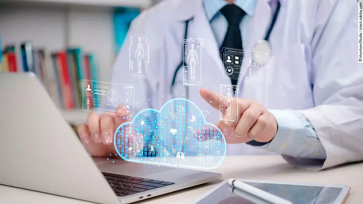 Arzt am Laptop der mit dem Finger auf eine Datencloud zeigt