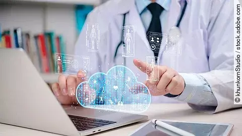 Arzt am Laptop der mit dem Finger auf eine Datencloud zeigt