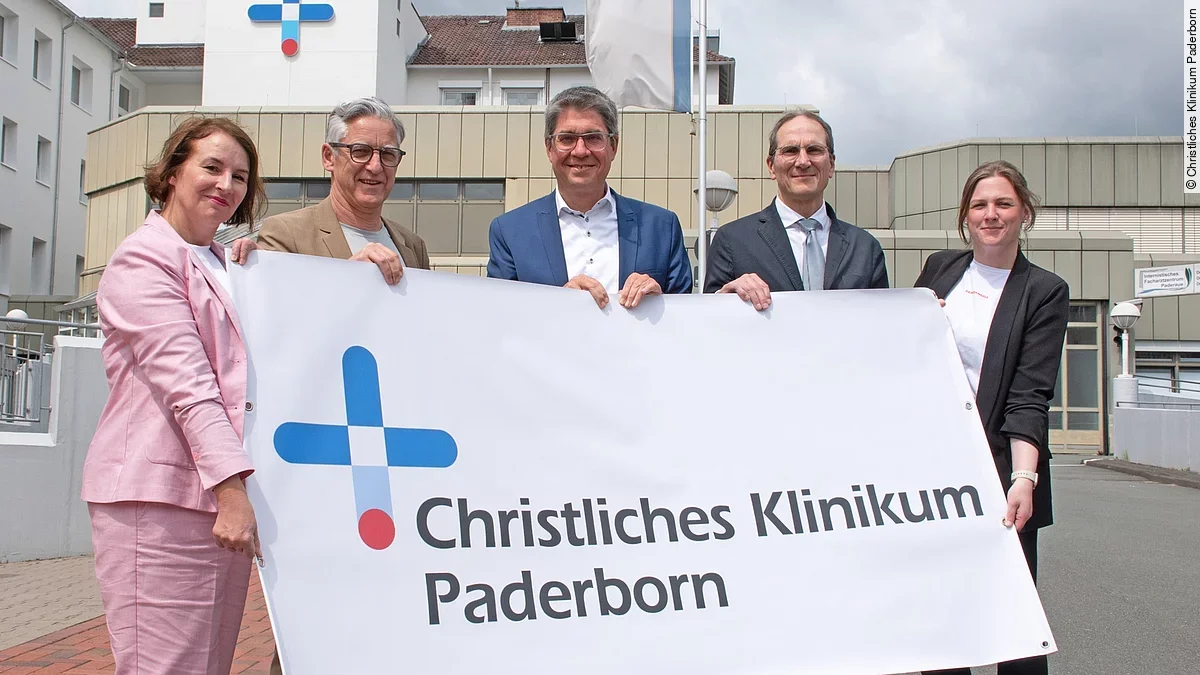 Brüderkrankenhaus St. Josef und Krankenhaus St. Johannisstift sind zum Christlichen Klinikum Paderborn fusioniert Fünf Menschen halten zusammen ein Poster hoch.