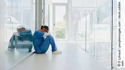 Ärztin am Ende ihrer Kräfte Ärztin sitzt traurig auf dem Boden eines Krankenhauses.