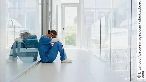 Ärztin am Ende ihrer Kräfte Ärztin sitzt traurig auf dem Boden eines Krankenhauses.