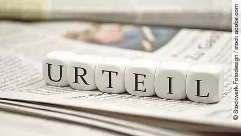 Buchstabenwürfel bilden das Wort "Urteil". Sie liegen auf einer Zeitung.