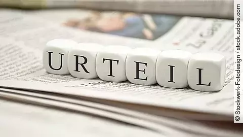 Buchstabenwürfel bilden das Wort "Urteil". Sie liegen auf einer Zeitung.