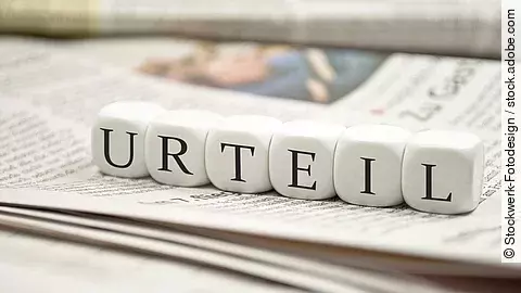 Buchstabenwürfel bilden das Wort "Urteil". Sie liegen auf einer Zeitung.