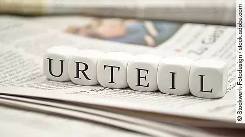 Buchstabenwürfel bilden das Wort "Urteil". Sie liegen auf einer Zeitung.