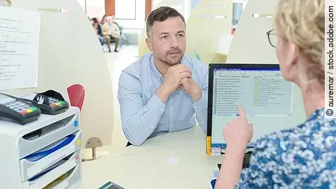 Patient sitz am Empfang im Krankenhaus zur Angabe seiner Daten