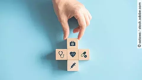 Gesundheitsversorgung Kreuz aus Holzwürfeln mit Symbolen der Gesundheitsversorgung