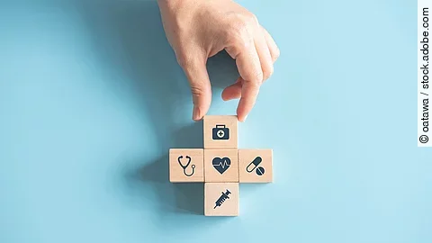 Kreuz aus Holzwürfeln mit Symbolen der Gesundheitsversorgung