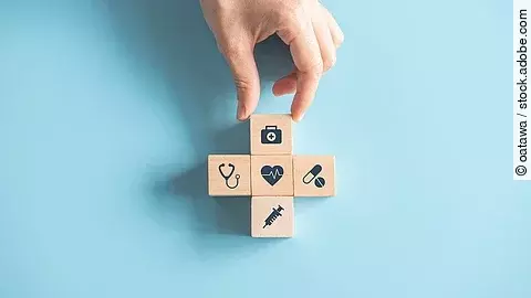 Kreuz aus Holzwürfeln mit Symbolen der Gesundheitsversorgung