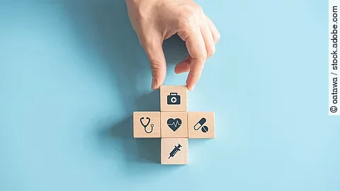 Kreuz aus Holzwürfeln mit Symbolen der Gesundheitsversorgung