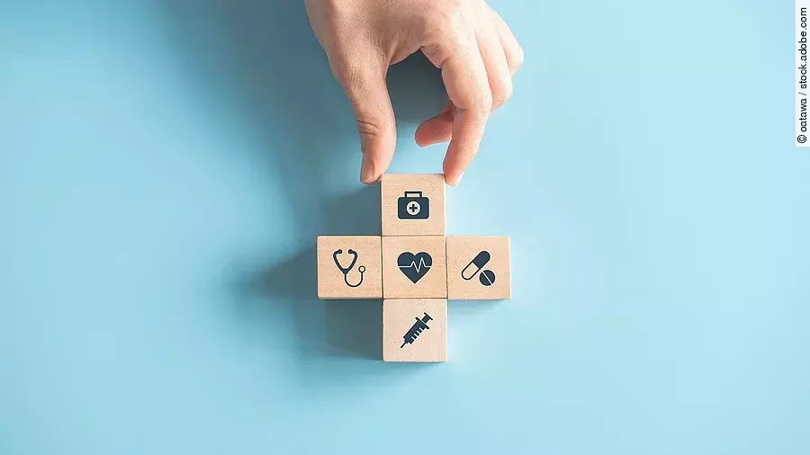 Gesundheitsversorgung Kreuz aus Holzwürfeln mit Symbolen der Gesundheitsversorgung